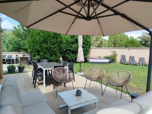 a patio with a table and chairs and an umbrella at Can Vinyals Holiday Home in Castellar
