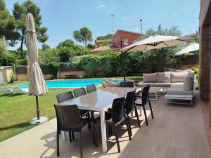 a patio with a table and chairs and an umbrella at Can Vinyals Holiday Home in Castellar