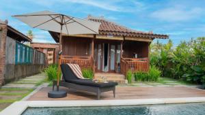 a house with a pool and a chair and an umbrella at Villa Uma Sawan By 25Hours Hospitality in Bedahulu