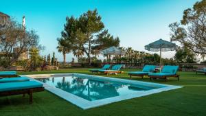 a swimming pool with blue lounge chairs next to a yard at Claudia by Nura in Campos