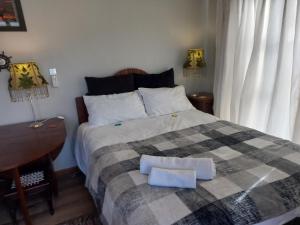 a bedroom with a bed with a blanket and a desk at Rosa Villa in Hermanus