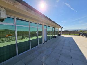 a large building with glass windows and a patio at Hotel Arbëri Events in Rahovec