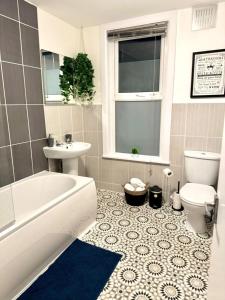 a bathroom with a tub and a toilet and a sink at Stylish Townhouse - 8 Mins From Leeds - Free Fast WiFi - Free Parking in Headingley
