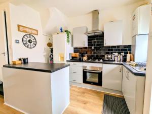 a kitchen with white cabinets and a black tile wall at Stylish Townhouse - 8 Mins From Leeds - Free Fast WiFi - Free Parking in Headingley