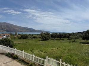 a white fence in a field with a lake at ERV Club - Villas in Lixouri