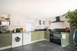 a kitchen with green cabinets and a washer and dryer at Riverside Cottage in Cairngorms in Ballater