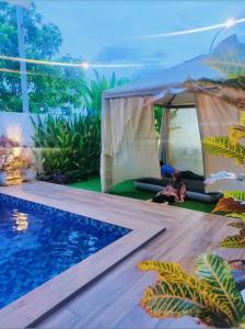 a woman sitting in a tent next to a swimming pool at Spring Fields Homestay by Sizma in Semenyih