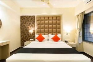a bedroom with a large bed with orange pillows at Hotel Radiant in Kolkata