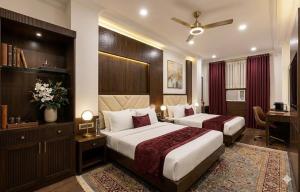 a hotel room with two beds and a desk at Hotel Grand Heaven in Tājganj