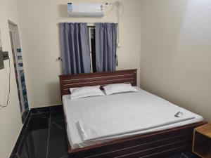 a small bedroom with a bed with white sheets and a window at 101 Mahalaxmi Homes in Bhubaneshwar