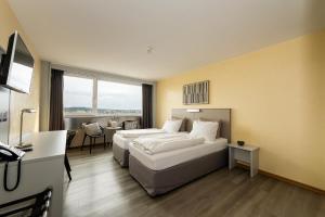a hotel room with two beds and a table at City Hotel Heilbronn in Heilbronn