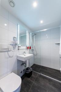 a white bathroom with a toilet and a sink at City Hotel Heilbronn in Heilbronn