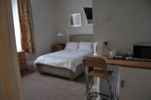 1 dormitorio con 1 cama y escritorio con silla en Westham, en Warwick