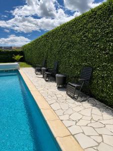 a swimming pool with chairs next to a hedge at Villa Patja in Béziers