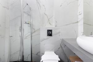 a white bathroom with a shower and a sink at Razin 37 in Eilat