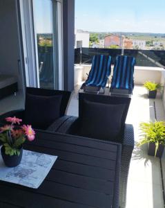 two chairs and a table on a balcony with plants at APP Mary in Novigrad Istria