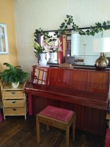 a piano in a living room with a mirror at Enstone Homestay in Sidmouth