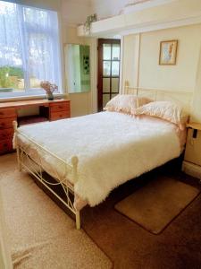 a bedroom with a bed and a desk and a window at Enstone Homestay in Sidmouth