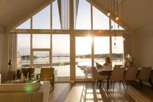 a woman sitting at a table with a laptop in a room with windows at Panorama Rorbusuiter in Steinsland