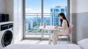 a woman sitting at a table in a room with a window at Shine Hotel Incheon Airport in Incheon
