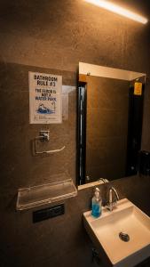 a bathroom sink with a mirror and a sign on the wall at Checkpoint backpacker in New Delhi
