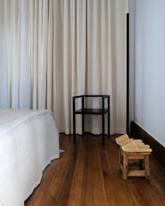 a bedroom with a bed and a stool and curtains at Hakanto House in Antananarivo +11 photos