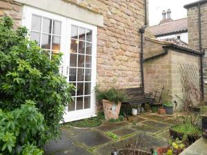 a garden with a bench next to a brick house at The Old Cookery Cottage & Free Parking in Goldsborough +11 photos