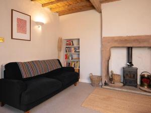 a living room with a black couch and a fireplace at The Old Cookery Cottage & Free Parking in Goldsborough