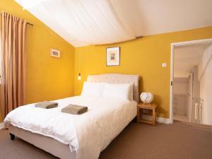 a bedroom with a white bed and a yellow wall at The Old Cookery Cottage & Free Parking in Goldsborough