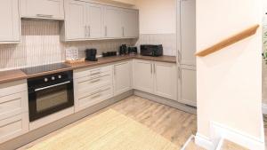 a kitchen with white cabinets and a stove top oven at Newly Renovated 2-Bed Flat | Ripon Town Centre in Ripon