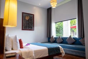 a bedroom with a blue couch and a window at Grange Boutique Siem Reap in Siem Reap