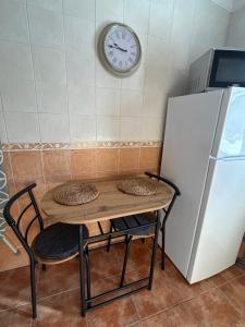 a table with two chairs and a clock on the wall at Casita Maite in Ardales