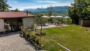 a garden with tables and umbrellas with mountains in the background at B&B Villa Pilotti in Penna San Giovanni