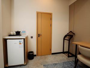 a kitchen with a small refrigerator and a wooden door at NOOMA Hotel Frunze in Bishkek