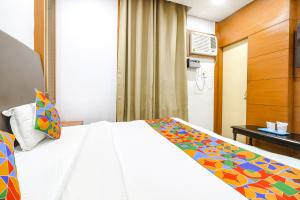 a bedroom with a white bed with a colorful blanket at FabHotel Nand's Residency in Patna