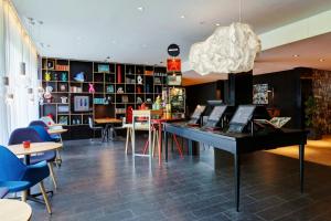 a room with a piano and tables and chairs at citizenM Amsterdam South in Amsterdam