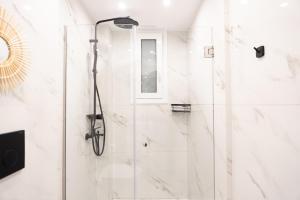 a white bathroom with a shower with a glass door at Syntagma Luxury Suites 1 in Athens