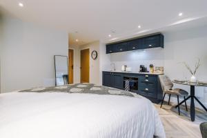 a bedroom with a white bed and a kitchen at Rock Mill - Deluxe Studio Apartment with Balcony in Stony Middleton