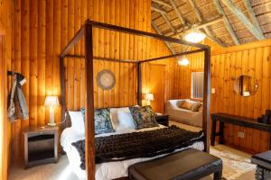 a bedroom with a canopy bed in a room with wooden walls at Addo Nyala Guest Lodge in Paterson +19 photos