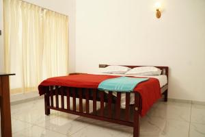 a bedroom with a bed with a red and blue blanket at Twilight Stays Cherai Beach in Pallipuram +15 photos
