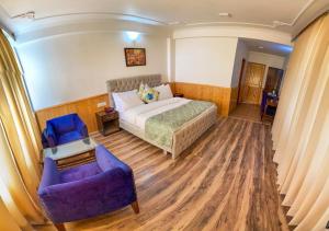 a bedroom with a bed and a couch and a chair at Snow Range Cottages in Manāli