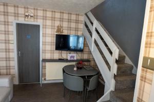 a room with a table and a staircase with a television at 1BR Charming Cottage in Central Moffat in Moffat