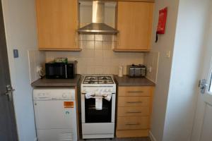 a small kitchen with a stove and a microwave at 1BR Charming Cottage in Central Moffat in Moffat +15 photos