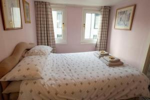 a bed in a bedroom with two towels and two windows at 1BR Charming Cottage in Central Moffat in Moffat