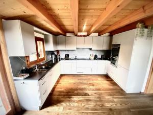 a kitchen with white cabinets and a wooden ceiling at Chalet Les Dalton, Morgins in Morgins +10 photos