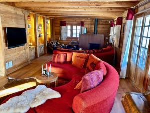 a living room with a red couch and a tv at Le Mélézin Bleu in Morgins