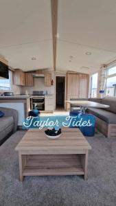 a living room with a table and a kitchen at Taylor Tides Caravan in Abergele