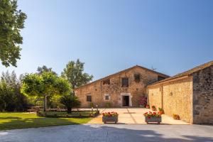 an old stone building with flowers in front of it at Can Mas in Fontcuberta