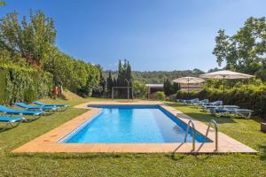 a swimming pool with blue chairs and umbrellas at Can Mas in Fontcuberta