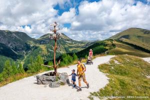 a man and two children standing next to a small tree at Appartments Bergland an der Brunnachbahn in Bad Kleinkirchheim